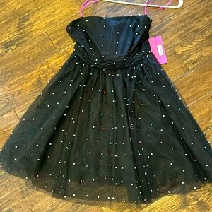 Black strapless dress with multicolored pearls and back bow .